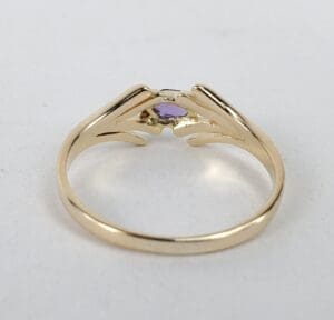 Gold ring with small purple gemstone.