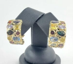 Gold earrings with colorful gemstones on display.