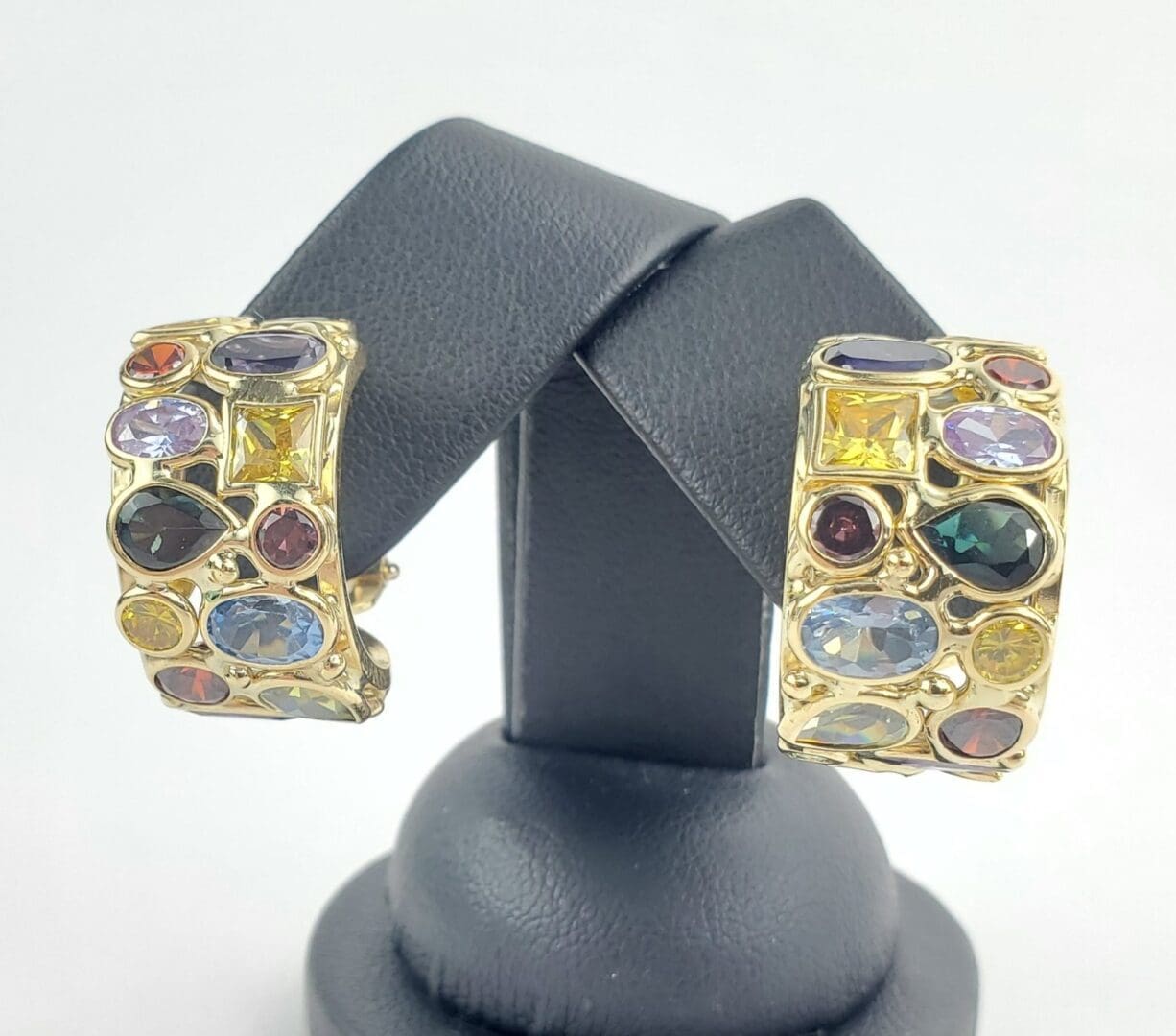 Gold earrings with colorful gemstones on display.