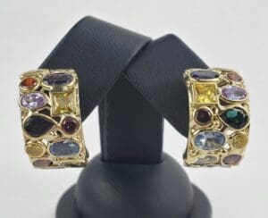 Gold earrings with colorful gemstones on display.
