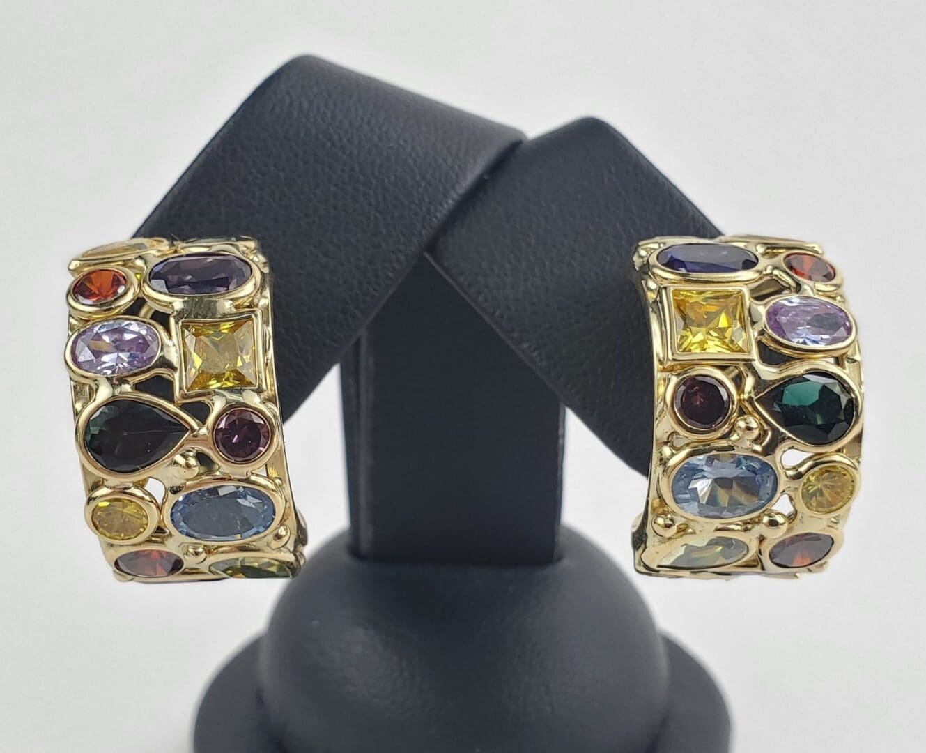 Gold earrings with colorful gemstones on display.