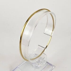 Gold and clear minimalist bracelet on stand.
