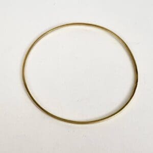 Gold circular bangle on white background.
