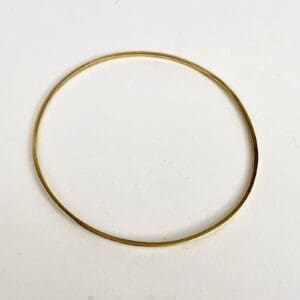 Thin gold bangle on white background.
