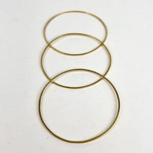 Three thin gold bangles on white background.