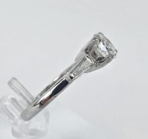 Silver ring with clear gemstone on stand.