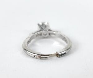 Silver ring with diamond on white background.