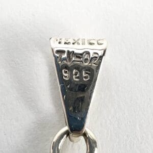 Silver pendant with engraved markings, close-up.