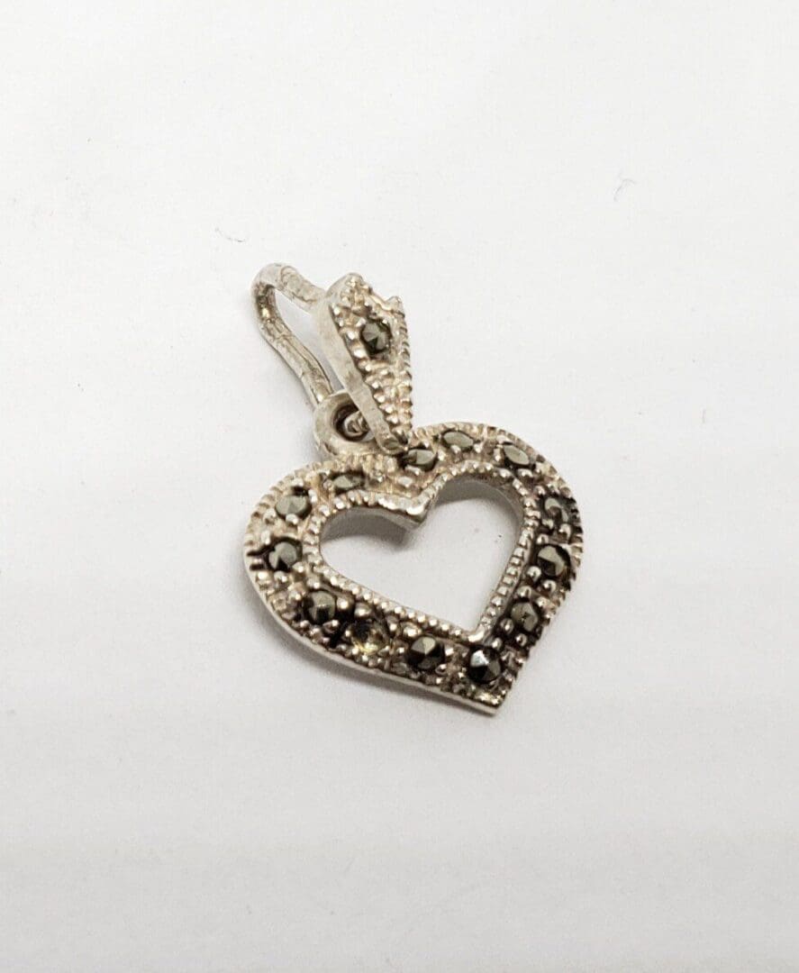 Heart-shaped silver pendant with intricate design.