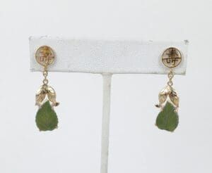 Gold earrings with green leaf pendants.