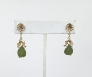 Gold earrings with green leaf pendants.
