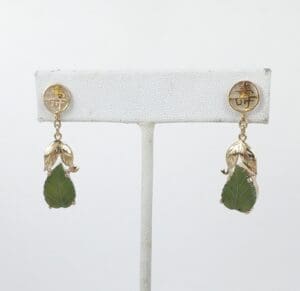 Gold earrings with green leaf pendants.