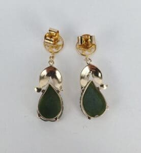 Gold earrings with green teardrop stones.