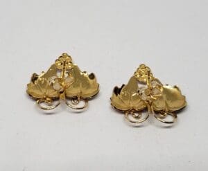 Gold leaf-shaped earrings on white background.