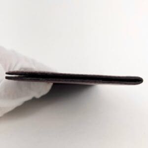 Gloved hand holding thin wallet sideways.