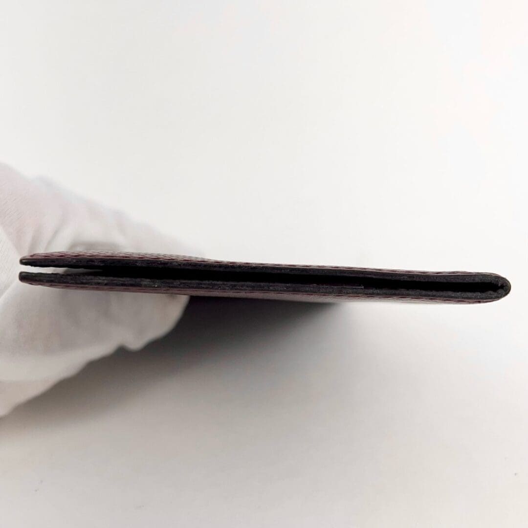 Gloved hand holding thin wallet sideways.