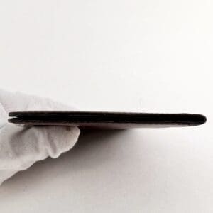 Gloved hand holding a thin, flat object.