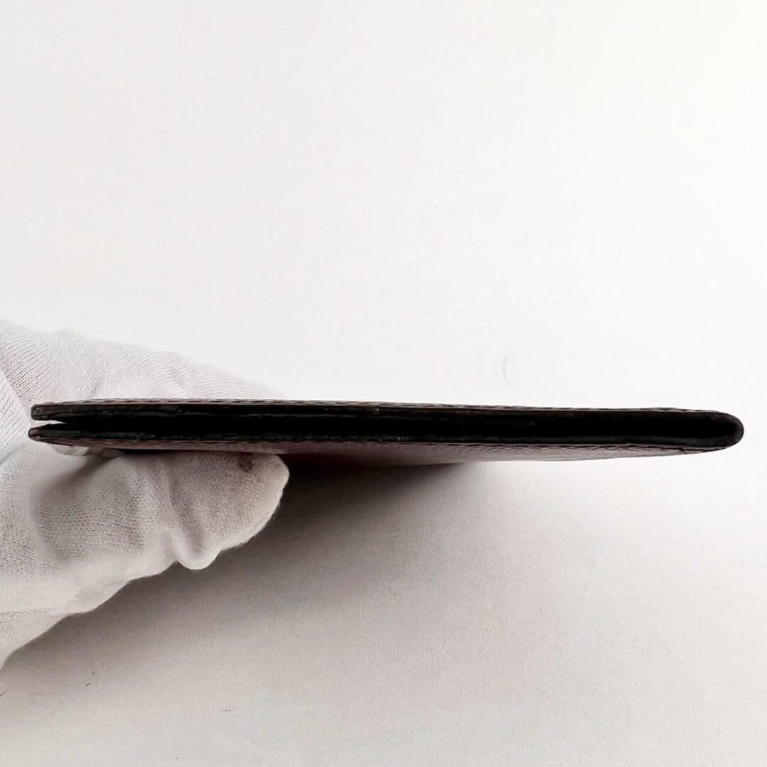 Gloved hand holding a thin, flat object.
