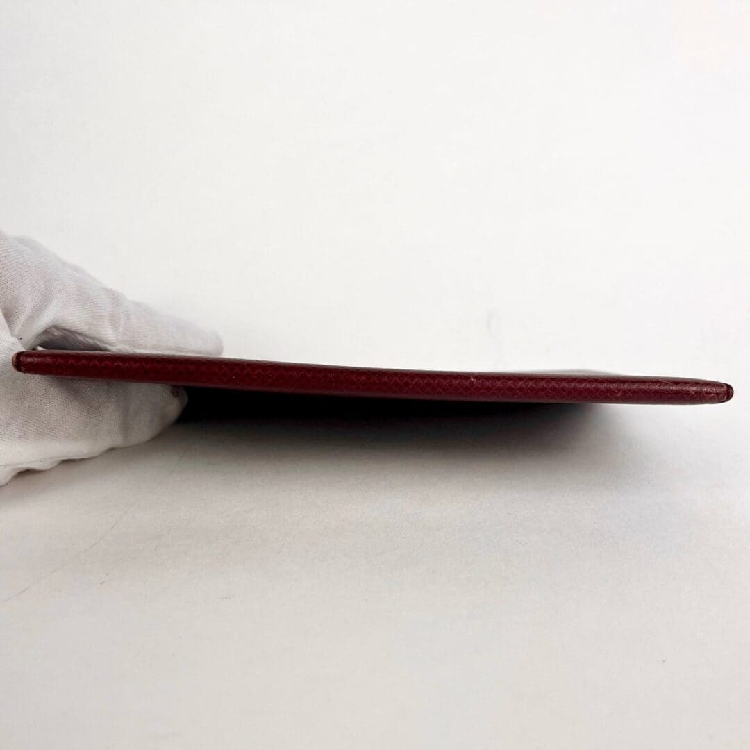 Red leather wallet held by gloved hand.
