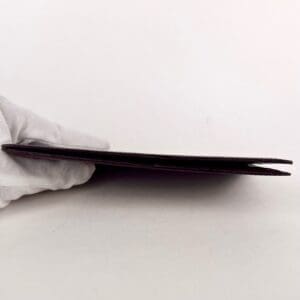 Gloved hand holding a thin black object.