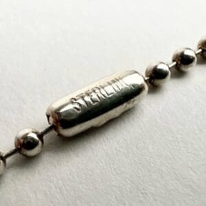 Silver necklace with "STEAL ME" engraved bead.