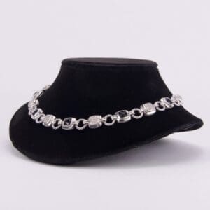 Silver bracelet displayed on black velvet stand.