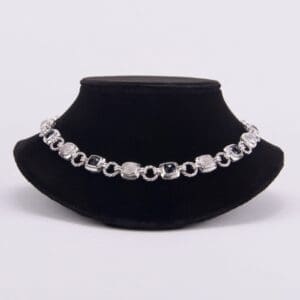 Silver bracelet displayed on black velvet stand.