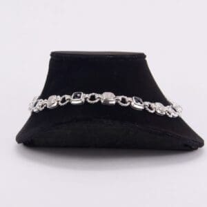 Silver bracelet with dark gemstones on display.