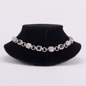 Silver bracelet on black velvet display stand.