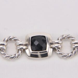 Silver bracelet with black stone centerpiece.