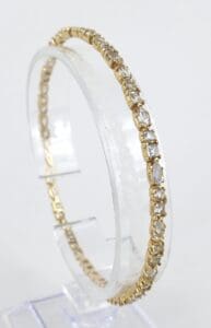 Gold bracelet with clear gemstones on display.