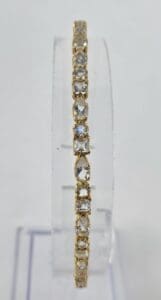 Gold bracelet with clear gemstones on display.
