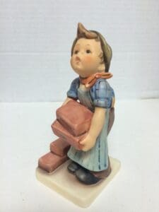 Child figurine holding pink bricks statue.