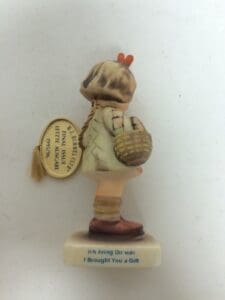 Child figurine holding a basket, side view.