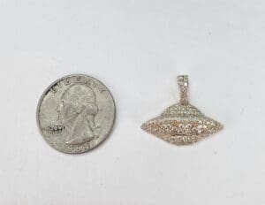 UFO pendant beside a US quarter coin.