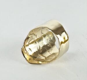 Gold, textured ring on white background.