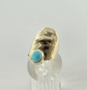 Gold ring with turquoise gemstone on display.