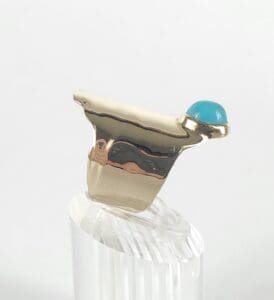 Gold ring with blue gemstone on stand.