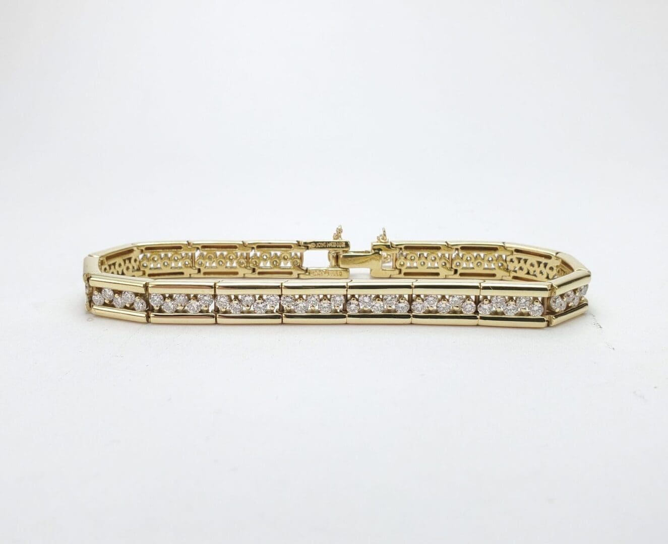 Gold bracelet with diamonds on white background.