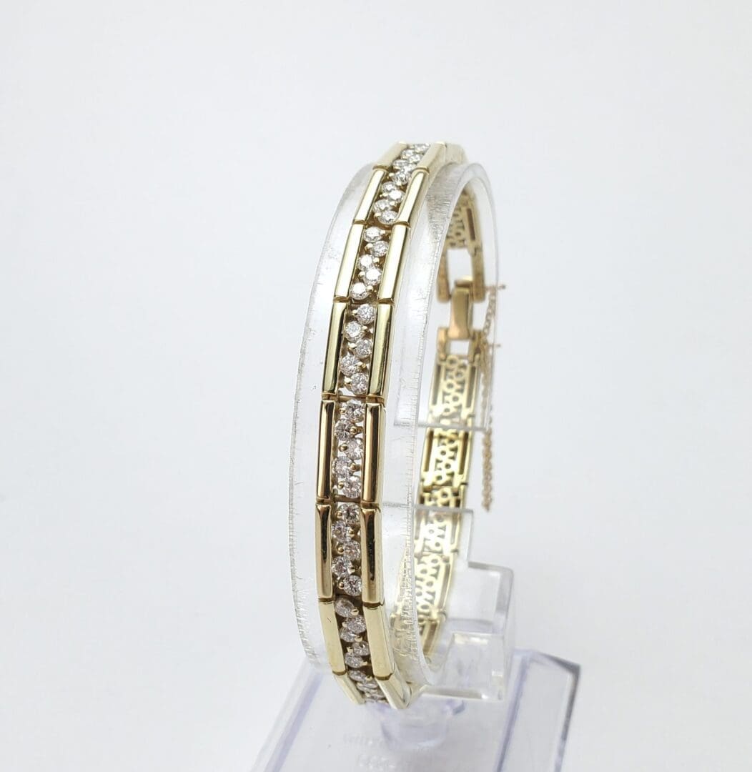 Gold and diamond bracelet on display stand.