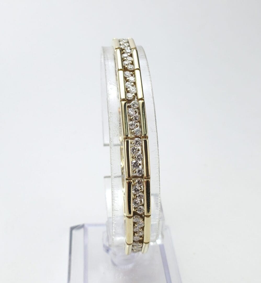 Gold bracelet with diamonds on display stand.