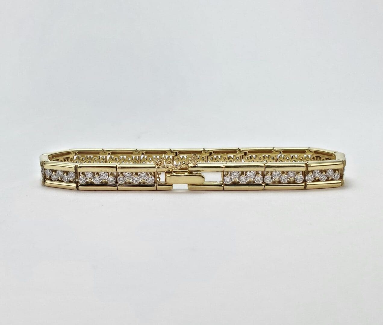 Gold bracelet with diamond accents, white background.