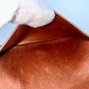 Empty brown leather wallet with white glove.