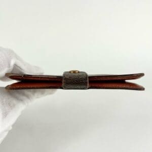 Gloved hand holding a slim leather wallet.