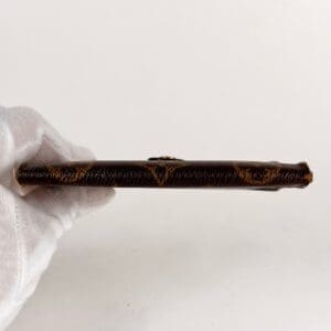 Gloved hand holding a thin, ornate object.