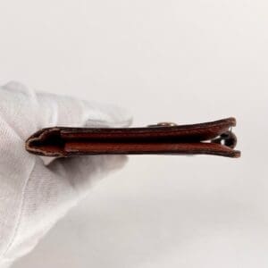 Gloved hand holding a brown leather wallet.