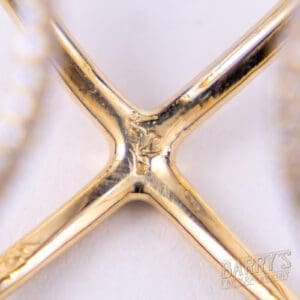 Gold jewelry close-up with "X" design.