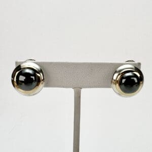 Silver and black round earrings on display.