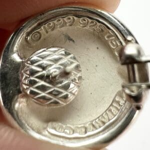 Close-up of silver earring with engravings.