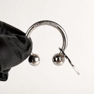Gloved hand holding a silver horseshoe barbell.